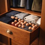 Boules de cedre anti mites disposees dans un tiroir avec pulls et vetements en laine plies